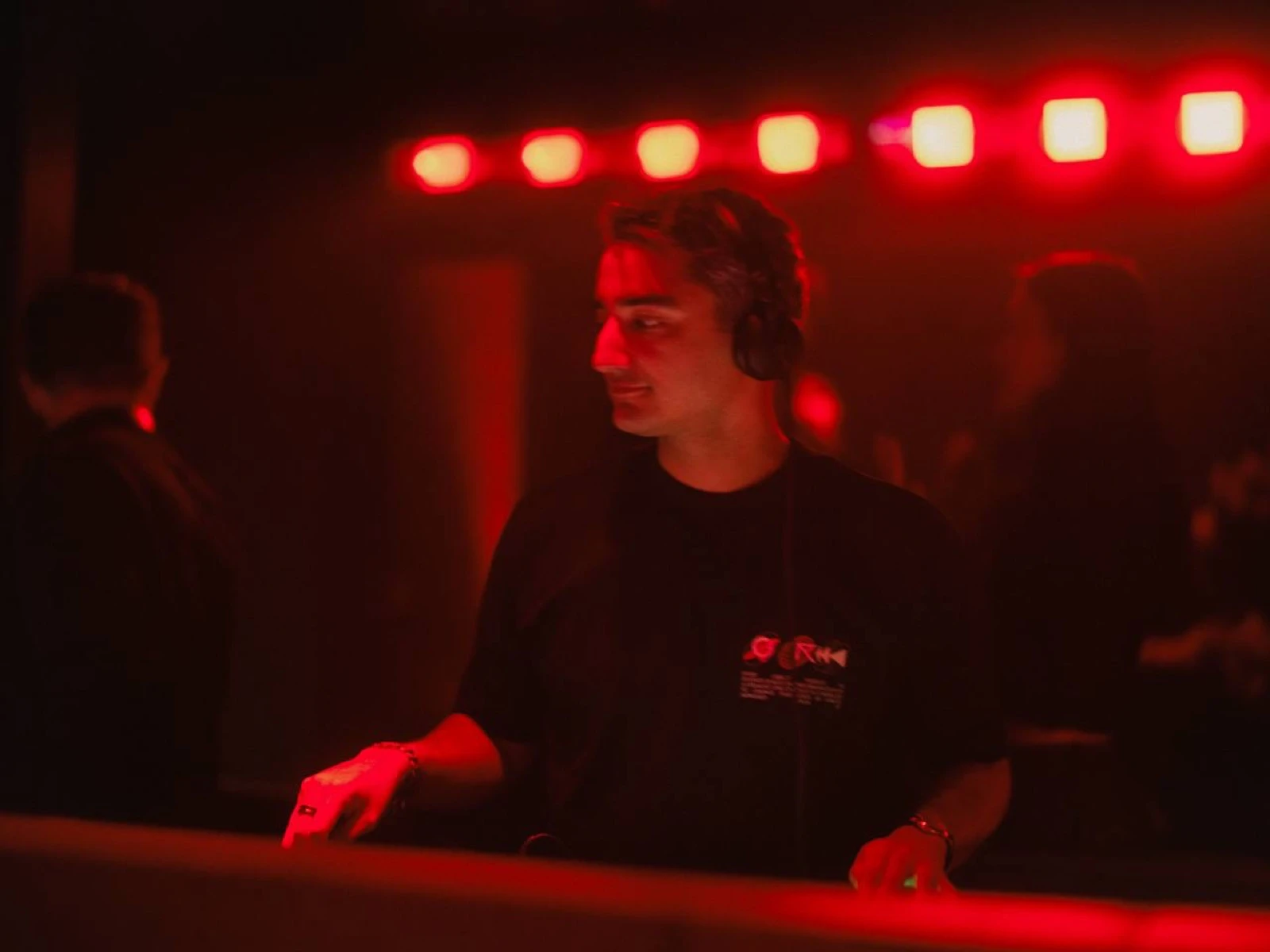 Gabi DJing in headphones under red lights